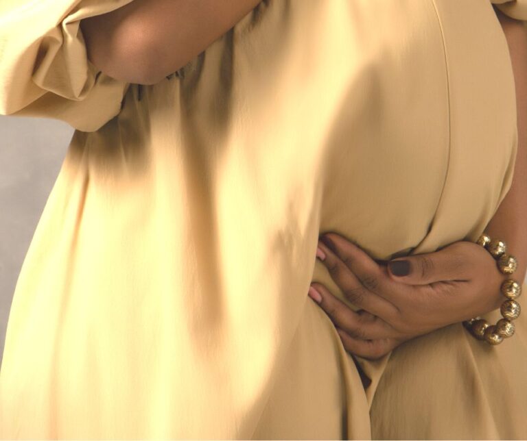 pregnant lady in a yellow dress holding her belly.